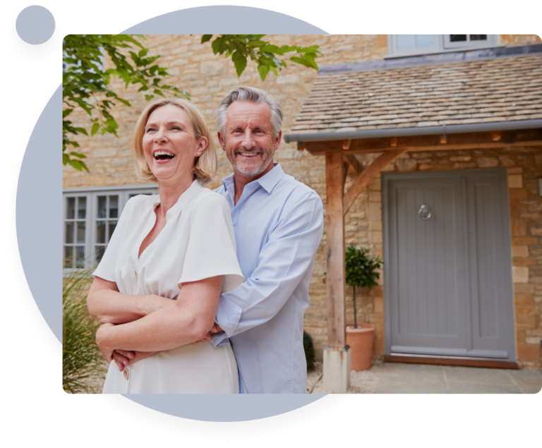 Elderly couple smiling together in front of their cozy home, enjoying their retirement.